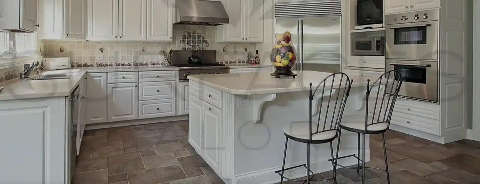 Bright, white kitchen with an island and stainless steel appliances.