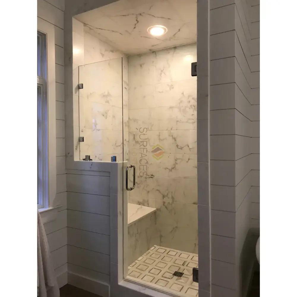 Modern glass shower enclosure featuring Calacatta Gold Select mosaic marble tiles