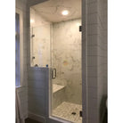 Glass-enclosed shower with Calacatta Gold Select marble-patterned walls