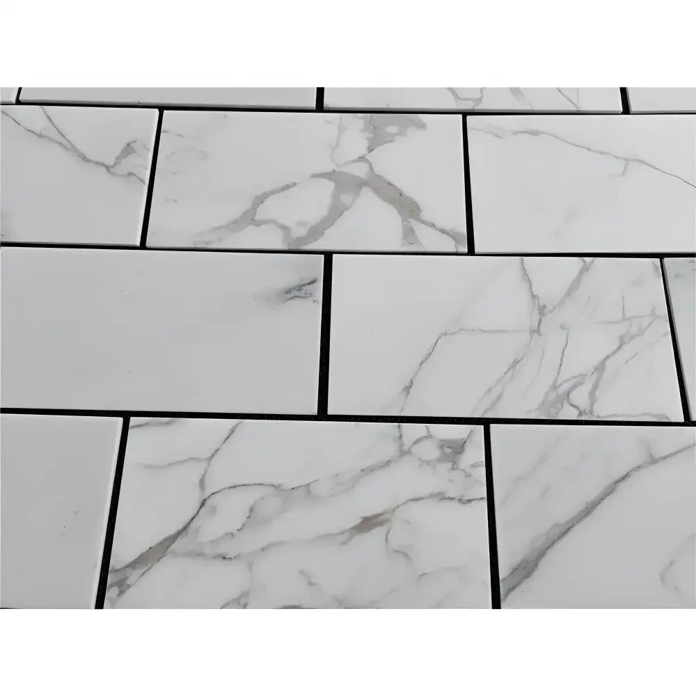 White marble-patterned tiles with dark grout from Calacatta Gold Select 12x24 collection
