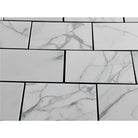 White marble-patterned tiles with dark grout from Calacatta Gold Select 12x24 collection