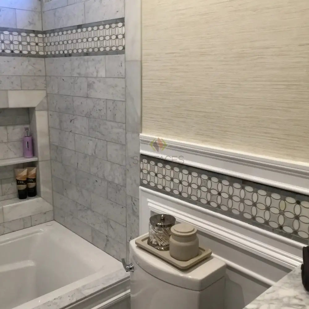 Bathroom interior featuring Carrara White Royale Marble 3x6 Tumbled tiles and decorative marble accents