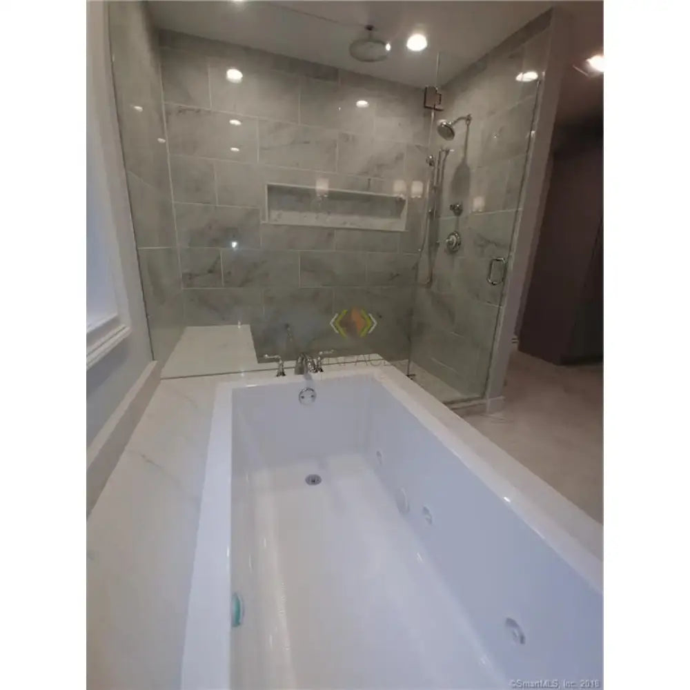 White bathtub with jets featuring Carrara White Royale Marble 3X6 Tumbled surface