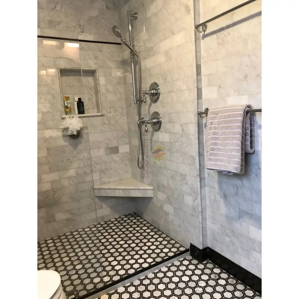 Marble-tiled shower with hexagon floor featuring Carrara White Royale Marble 3x6 Tumbled