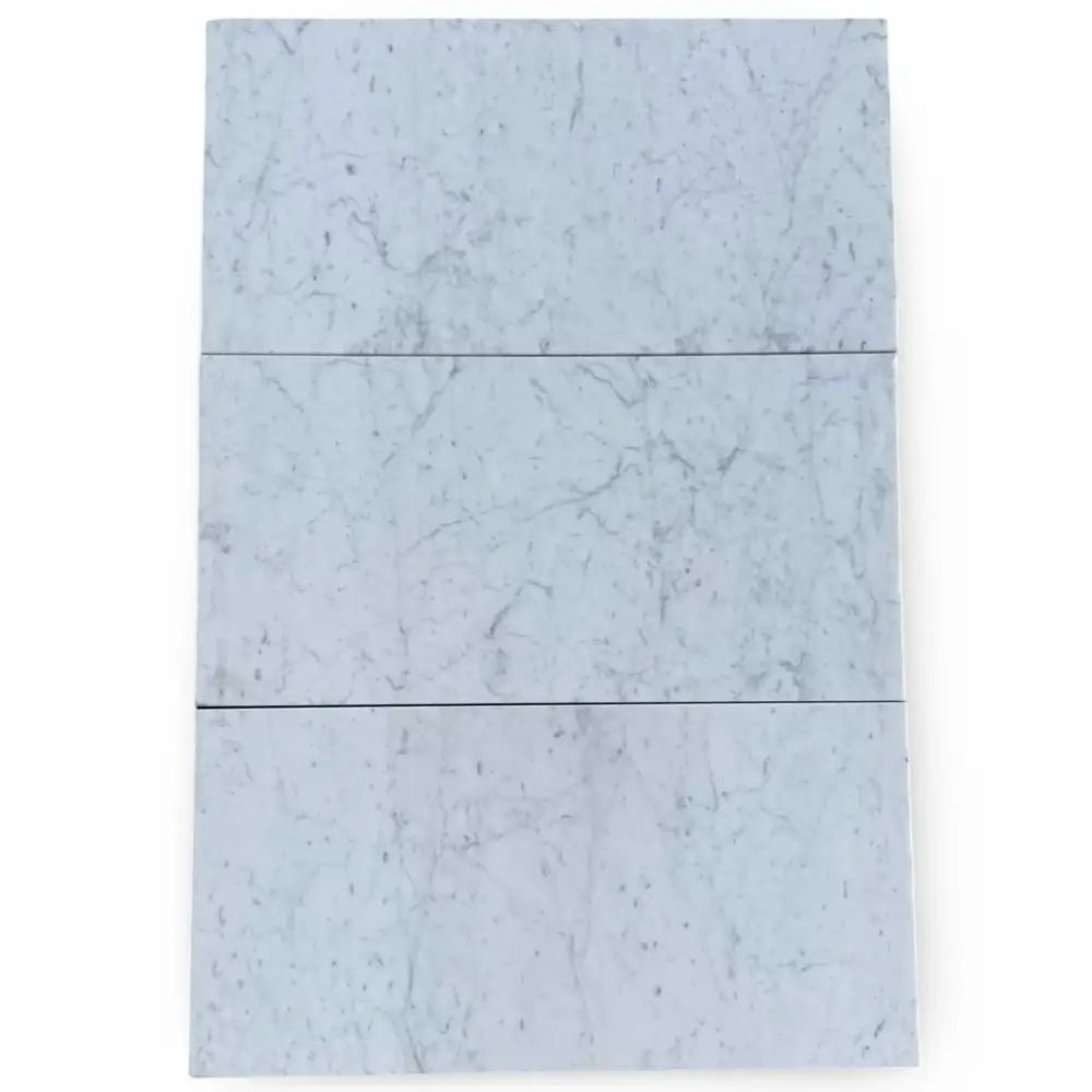 Three Carrara White Royale marble tiles in 3x6 tumbled finish for elegant flooring